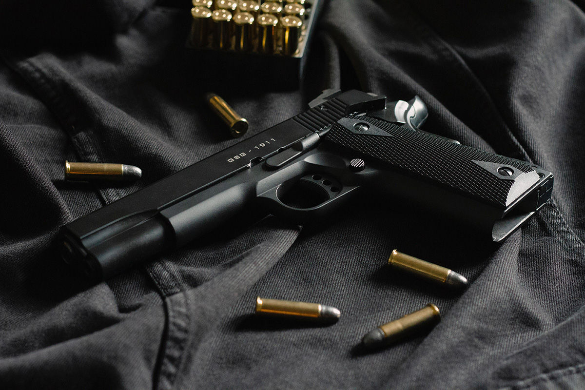 Black gun on denim surrounded by bullets