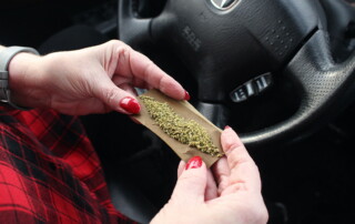 woman rolling a marijuana joint inside a car | The Law Office of Purav Bhatt