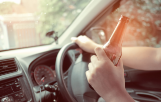 Person driving with beer bottle in hand - Chicago Criminal Defense Attorney