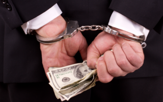 business man in handcuffs with hundred dollar bills in hand - Chicago Criminal Defense Attorney
