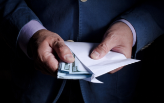 man in a suit holding money in an envelope