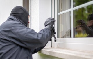 Masked burglar attempting to break into a home through a window – image for The Law Office of Purav Bhatt discussing criminal defense and burglary charges in Chicago.