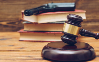 Judge gavel, law books and gun on a wooden background